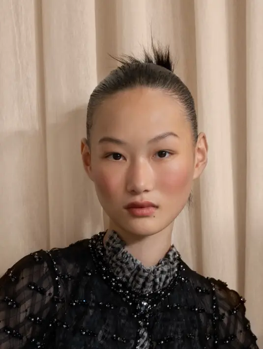 Kompleksi wajah menjadi kunci dari tampilan ini. Makeup artist menggunakan Les Beiges Touche de Teint, foundation ringan yang memberikan efek second-skin, dipadukan dengan Le Correcteur de Chanel untuk menyamarkan ketidaksempurnaan tanpa menutupi tekstur alami kulit. Untuk menciptakan rona sehat seperti habis liburan musim panas, mereka mengaplikasikan Les Beiges Crème Belle Mine Ensoleillée dan blush Joues Contraste Intense Rose Radiant yang memberikan semburat pink alami di pipi.