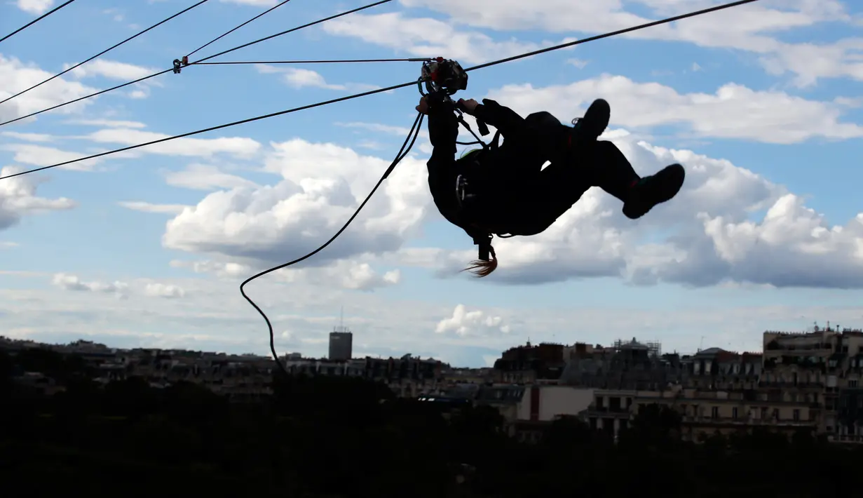 Pengunjung meluncur dengan seutas tali saat menjajal Zip Line dari lantai dua Menara Eiffel di atas taman Champ de Mars, Paris, Selasa (28/5/2019). Lintasan ini memungkinkan traveler untuk meluncur melintasi satu tempat ke tempat lainnya menggunakan tali dan alat olahraga outdoor. (AP/Francois Mori)