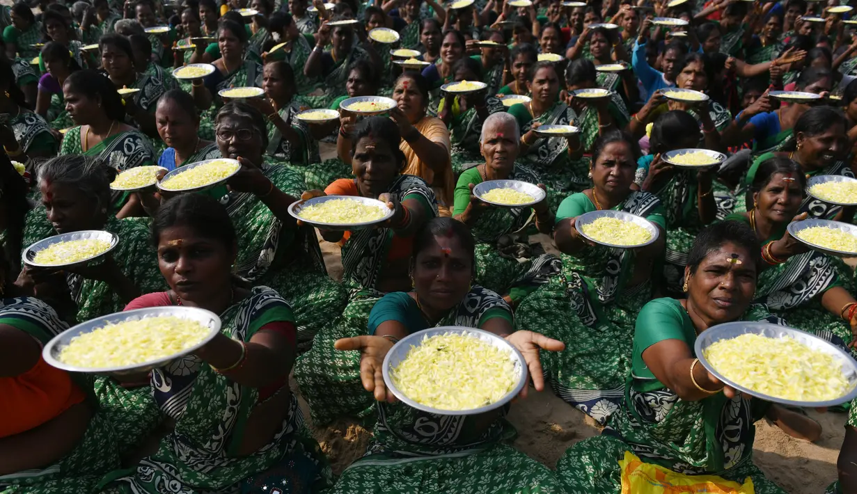 Para wanita membawa bunga persembahan dalam upacara penghormatan untuk korban tsunami tahun 2004 di Pantai Pattinapakkam, Chennai, India, Rabu (26/12). Lebih dari 10 ribu warga India tewas dalam tsunami Samudra Hindia pada 2004 lalu. (ARUN SANKAR/AFP)