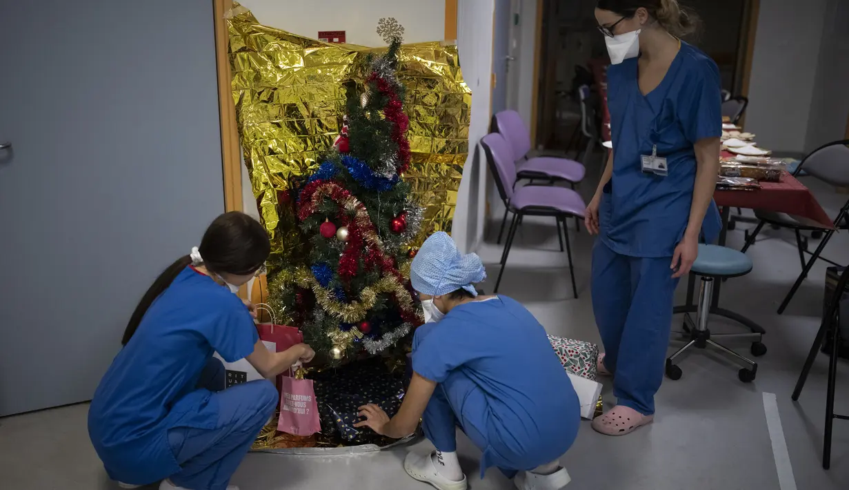 Pekerja rumah sakit meletakkan hadiah di bawah pohon natal di unit perawatan intensif COVID-19 di rumah sakit la Timone di Marseille, Prancis selatan, Jumat (24/12/2021). (AP Photo/Daniel Cole)
