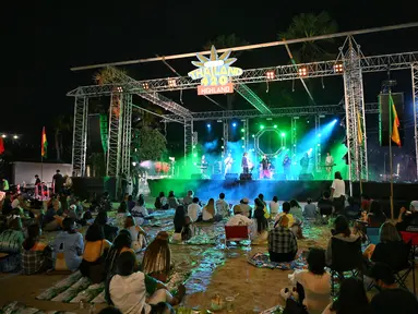 Orang-orang mendengarkan band saat mereka berkumpul untuk merayakan legalisasi ganja di “Thailand: 420 Legalaew!” festival akhir pekan yang diselenggarakan oleh Highland di provinsi Nakhon Pathom 11 Juni 2022. (AFP/Lillian Suwanrumpha)