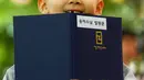 Seorang biksu pemula memegang buku  saat upacara pemberkatan Biksu di kuil Jogye, Seoul, Senin (11/5/2015). Sepuluh orang anak diberikan kesempatan untuk mengalami kehidupan sebagai biksu selama dua minggu. (REUTERS/Thomas Peter)