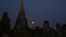 Bulan purnama terbit di belakang candi Wat Mahathat, Ayutthaya, Thailand (25/12/2015). Kerajaan Ayutthaya terkenal dengan harta karun yang berlimpah dan memiliki banyak arca dan patung-patung Buddha. (REUTERS/Jorge Silva)