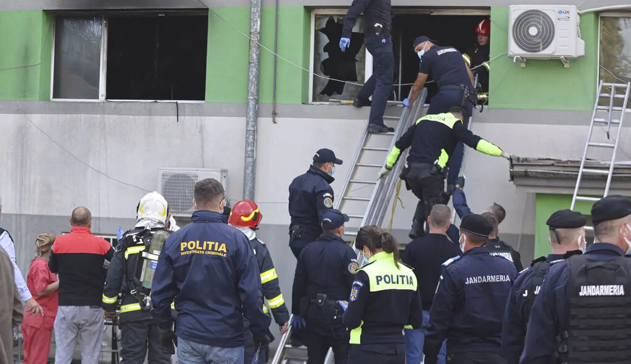Personel darurat keluar melalui jendela setelah kebakaran di bagian ICU COVID-19 Rumah Sakit Penyakit Menular di pelabuhan Laut Hitam Constanta, Rumania (1/10/2021). Pihak berwenang mengatakan kebakaran telah menewaskan sembilan pasien COVID-19 di ICU. (AP Photo/Costin Dinca)