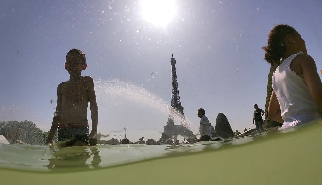 Turis dan warga masuk ke dalam kolam Trocadero Fountains (air mancur Trocadero) dekat Menara Eiffel di Paris, Kamis (25/7/2019). Gelombang panas di Eropa mencapai puncaknya, bahkan suhu di ibu kota Prancis mencapai di atas 41 derajat Celcius. (Dominique FAGET / AFP)