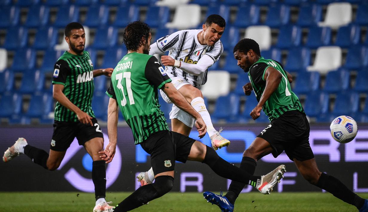 Striker Juventus, Cristiano Ronaldo (tengah) melepaskan tendangan di antara dua pemain Sassuolo dalam laga lanjutan Liga Italia 2020/2021 pekan ke-36 di Mapei-Citta del Tricolore Stadium, Rabu (12/5/2021). Juventus menang 3-1 atas Sassuolo. (AFP/Marco Bertorello)