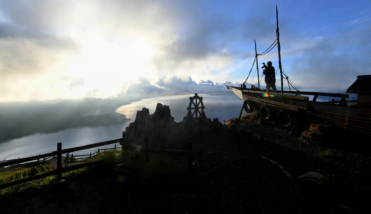 Pengunjung menikmati pemandangan Danau Toba dari Kabanjahe di Kabupaten Karo, Sumatra Utara, 3 April 2019. Danau terbesar di Asia Tenggara yang dikelilingi tujuh kabupaten di Sumatera Utara tersebut luasnya hampir dua kali ukuran Negara Singapura. (GOH CHAI HIN / AFP)