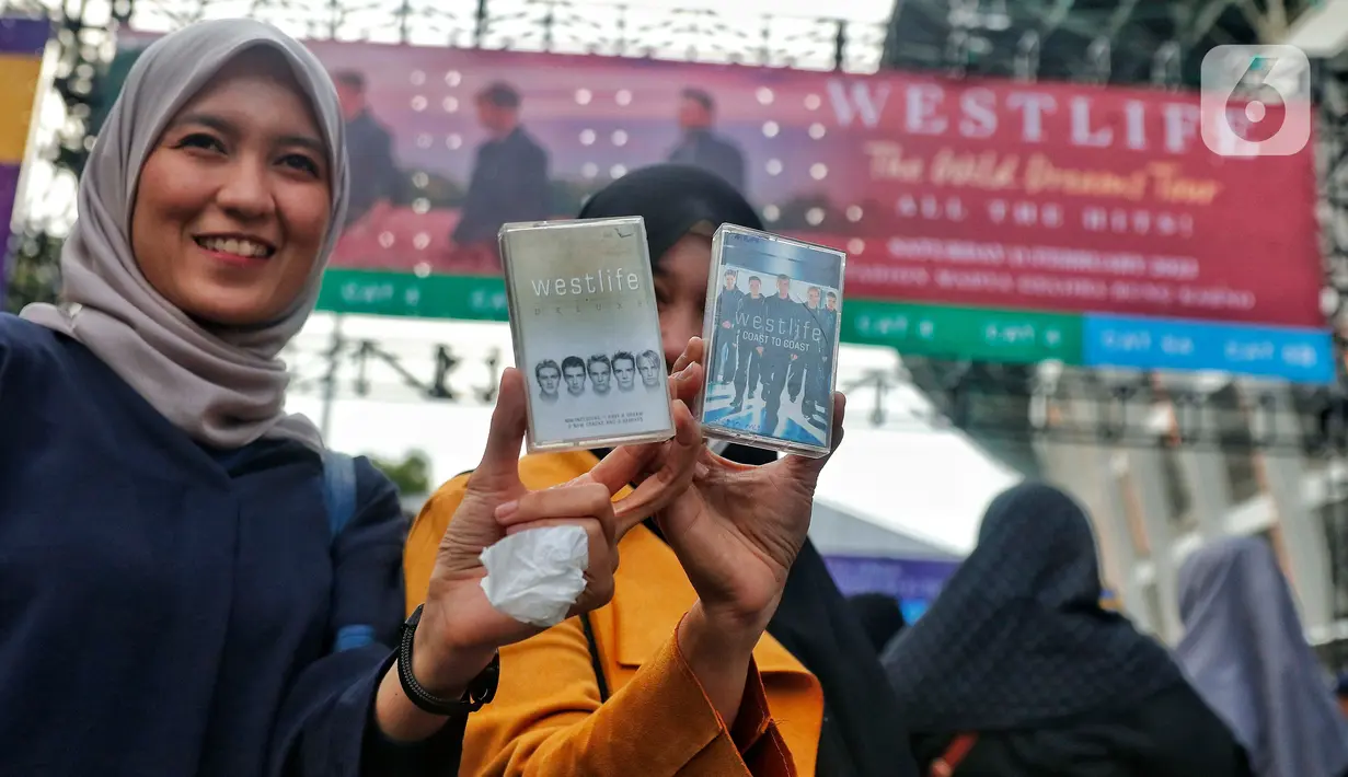 Penggemar Westlife menunjukkan album dalam bentuk fisik kaset tape saat tiba untuk menonton konser bertajuk 'The Wild Dreams Tour 2023' di kawasan Stadion Utama Gelora Bung Karno Sabtu (11/2/2023). Konser musik Westlife akan membawakan semua lagu hits mereka seperti Swear It Again, Flying Without Wings, dan World of our own serta lagu-lagu andalan dari album terbaru mereka yang bertajuk Wild Dreams. (Liputan6.com/Angga Yuniar)