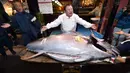 Pengusaha restoran sushi Jepang, Kiyoshi Kimura memamerkan ikan tuna sirip biru seberat 276 kilogram di restoran utamanya di Tokyo, Minggu (5/1/2020). Tuna raksasa itu dibeli dalam lelang perdana 2020 dengan harga USD 1,8 juta atau sekitar Rp 24 miliar. (Kazuhiro NOGI / AFP)