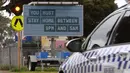 Sebuah mobil polisi melewati tanda jam malam saat kota itu mengalami penguncian keenam saat memerangi wabah varian Delta dari coronavirus.di Melbourne (25/8/2021). (AFP/William West)