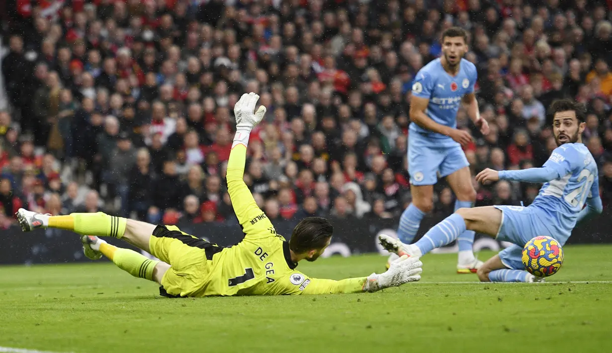 Kiper Manchester United, David de Gea, berusaha menghalau bola saat melawan Manchester City pada laga Liga Inggris di Stadion Old Trafford (6/11/2021). (AFP/Oli Scarff)