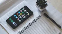 Membuka hp di atas buku (pexels)