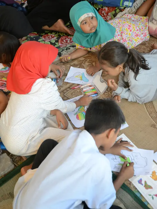 Anak-anak pengungsi korban gempa belajar di tenda pengungsian di Lapangan Tanjung, Lombok Utara, Rabu (8/8). Lebih dari 70.000 orang kehilangan tempat tinggal akibat gempa Lombok berkekuatan 7 SR yang melanda pada Minggu (5/8). (AFP/SONNY TUMBELAKA)