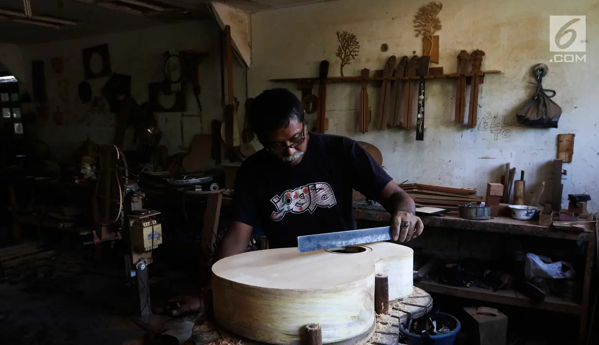 Pekerja tengah mengukir gitar di workshop I Wayan Tuges  gitar berlabel Blueberry di Jalan Baruna No. 5 Guwang, Sukowati, Bali, Senin (15/10). Gitar tersebut banyak dipesan oleh musisi lokal hingga mancanegara. (Liputan6.com/Angga Yuniar)