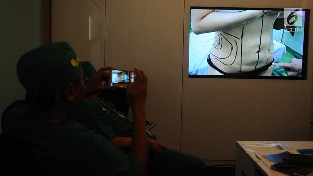 Seorang dokter mengabadikan gambar proses tindakan operasi bedah plastik di RS EMC Sentul, Bogor, Jawa Barat, Senin (14/1). Operasi bedah plastik ini ditujukan untuk membentuk perut jadi six pack. (Liputan6.com/Herman Zakharia)