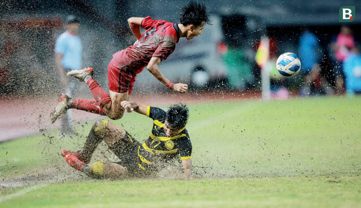 Pemain Timnas Laos U-19, Peeter Phanthavong, terjatuh saat berebut bola dengan pemain Timnas Malaysia U-19, Fakrul Fareez, pada laga final Piala AFF U-19 2022 di Stadion Patriot Chandrabhaga, Bekasi, Jumat (15/7/2022). (Bola.com/Bagaskara Lazuardi)