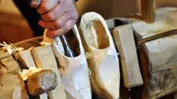 Pengrajin menghaluskan bagian dalam dari kayu yang akan dijadikan sepatu khas Belanda yang dikenal dengan sebutan Kelompen di kawasan Aarle-Rixtel, Belanda, Selasa (14/2). (AFP PHOTO / Maude BRULARD)