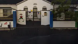 Pintu masuk sekolah tertutup abu gunung Cumbre Vieja di Las Manchas de Abajo di pulau Canary La Palma, Spanyol, Rabu (27/10/2021). Penduduk di Pulau La Palma menghadapi kemungkinkan gempa yang lebih kuat yang bisa memperparah kerusakan oleh muntahan lava gunung tersebut. (AP Photo/Emilio Morenatti)