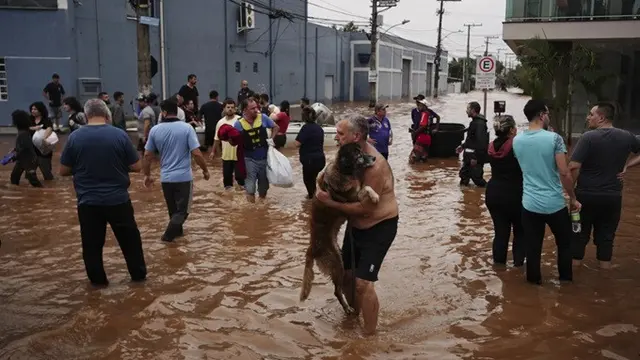 Seorang tentara membantu seorang wanita mengungsi dari lingkungan yang terendam hujan lebat di Canoas, Negara Bagian Rio Grande do Sul, Brasil, Sabtu (4/5/2024).