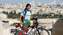 Pria Taiwan, Jacky Chen, berpose dengan sepedanya di Bukit Zaitun yang menghadap ke Kota Tua Yerusalem dan Kubah Batu pada 10 Juni 2019. Chen memulai misinya bersepeda keliling dunia sejak 2015 dan telah singgah di 64 negara dengan menempuh perjalanan sejauh 54.000 km. (MENAHEM KAHANA/AFP)
