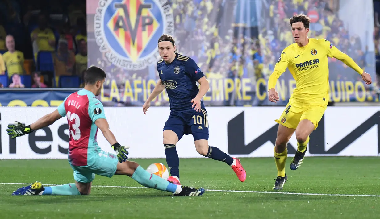 Gelandang Dinamo Zagreb, Lovro Majer (tengah) melepaskan tendangan yang masih mampu dihadang kiper Villarreal, Geronimo Rulli dalam laga leg kedua perempatfinal Liga Europa 2020/2021 di La Ceramica Stadium, Villarreal, Kamis (15/4/2021). Dinamo Zagreb kalah 1-2 dari Villarreal. (AFP/Jose Jordan)