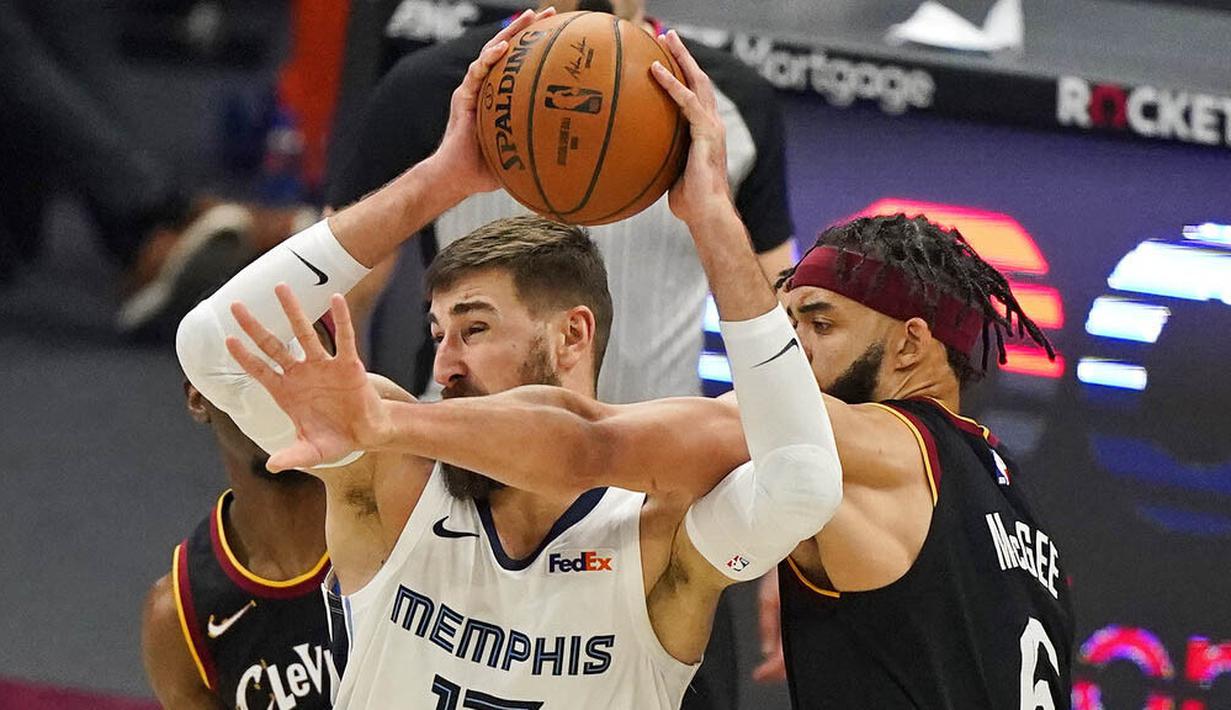 Pebasket Memphis Grizzlies, Jonas Valanciunas, berebut bola dengan pebasket Cleveland Cavaliers, JaVale McGee, pada laga NBA, Senin (11/1/2021). Grizzlies menang dengan skor 101-91. (AP/Tony Dejak)