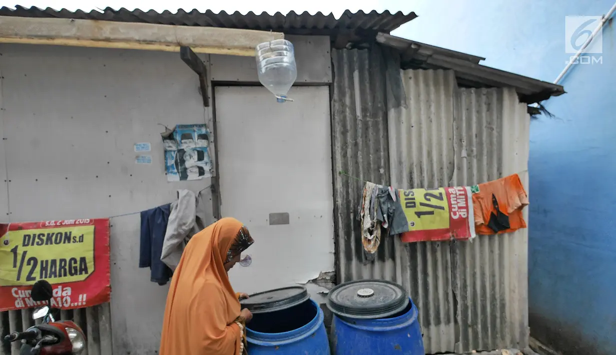 Warga memeriksa tong air di kawasan Kampung Kamal Muara, Jakarta, Selasa (9/7/2019). Sebagian besar warga Kampung Kamal Muara memasang pipa pada talang air di tepi atap rumah mereka untuk menampung air hujan. (Liputan6.com/Herman Zakharia)