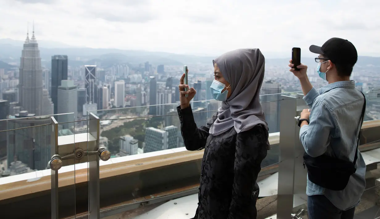 Turis dengan mengenakan masker mengambil gambar dari dek obseravsi di Menara Kuala Lumpur di Kuala Lumpur, Rabu (1/7/2020). Malaysia memasuki pelonggaran Perintah Kontrol Gerakan (MCO) setelah tiga bulan pembatasan karena virus corona Covid-19. (AP Photo/Vincent Thian)