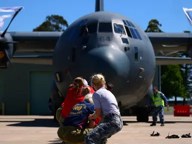 Para anggota Royal Australian Air Force menarik sebuah pesawat Hercules C-130J saat mengikuti lomba ketangkasan di Pangkalan Udara Richmond, Sydney (24/11). Lomba ini sebagai kegiatan melatih ketangkasan sekaligus kebersamaan. (REUTERS/David Gray)