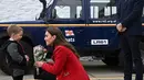 Kate Middleton mendapat bunga dari seorang bocah menjadi momen menyentuh. Ia menerima bunga tersebut dengan mengenakan long coat merah. [instagram/princeandprincessofwales]