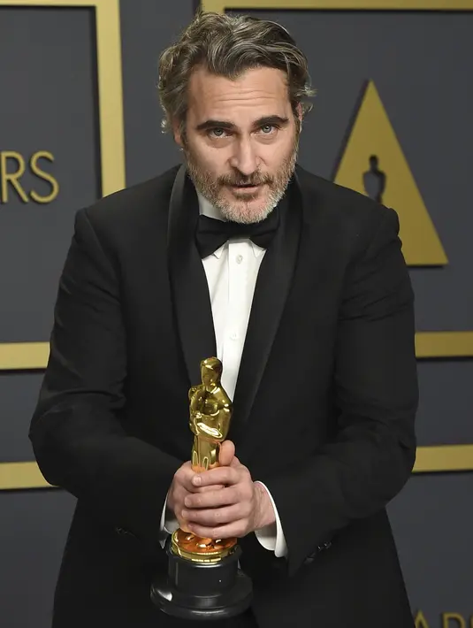Aktor Joaquin Phoenix berpose dengan piala Oscar 2020 di ruang pers di  Dolby Teater, Los Angeles, Minggu (9/2/2020). Joaquin mengalahkan Adam Driver di Marriage Story dan Leonardo DiCaprio di film Once Upon a Time in Hollywood!. (AP Photo/Jordan Strauss)