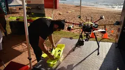 Ben Trollope menyiapkan pesawat tak berawak (drone) pendeteksi hiu di Pantai Bilgola, utara Sydney, Australia, 10 Desember 2017. Drone ini mampu membedakan hiu dengan makhluk laut lain, seperti lumba-lumba, paus, pari, dan sebagainya. (PETER PARKS/AFP)