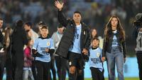 Pemain Uruguay, Luis Suarez (tengah) bersama ketiga anaknya melambaikan tangan kepada para penonton saat acara perpisahannya dengan Timnas Uruguay sebelum laga kualifikasi Piala Dunia 2026 melawan Paraguay yang berlangsung di Stadion Centenario, Montevideo, Uruguay, Sabtu (07/09/2024) WIB. (AFP/Dante Fernandez)