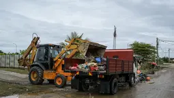 Sebuah ekskavator mengangkut puing-puing ke truk setelah air banjir surut di Mentakab, negara bagian Pahang Malaysia (11/1/2020). Tiga sungai di negara bagian itu - Sungai Lepar, Sungai Lipis dan Sungai Lembing - telah melewati tingkat bahaya. (AFP/Mohd Rasfan)