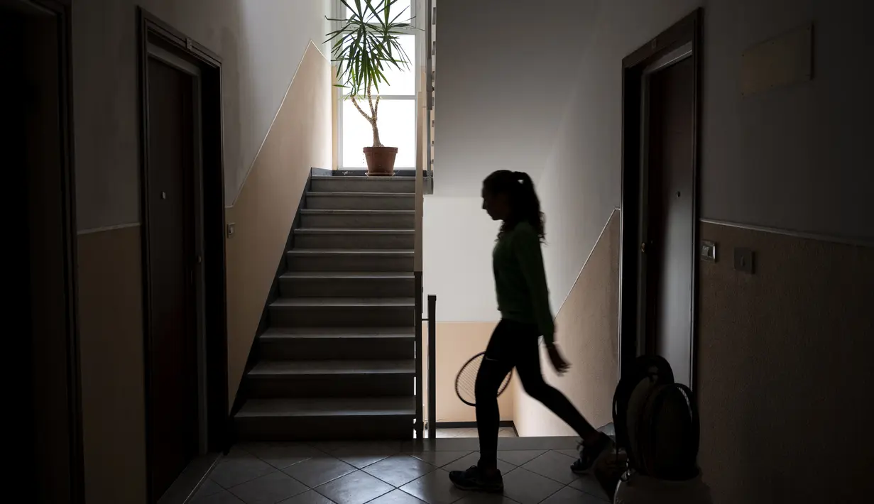 Vittoria Oliveri bersiap bermain tenis dengan Carola Pessina di atap rumah mereka selama lockdown COVID-19 di Finale Ligure, Wilayah Liguria, Italia (19/4/2020). Setiap hari Carola, 11, dan Vittoria, 13, bermain tenis dari satu atap ke atap lain di rumah mereka untuk berlatih. (AFP/Marco Bertorello)