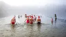 Tiga anggota asosiasi "Berliner Seehunde" berenang di antara bongkahan es saat mandi Natal di Danau Orankesee, Berlin, Jerman, Minggu (25/12/2022). (Christophe Gateau/dpa via AP)
