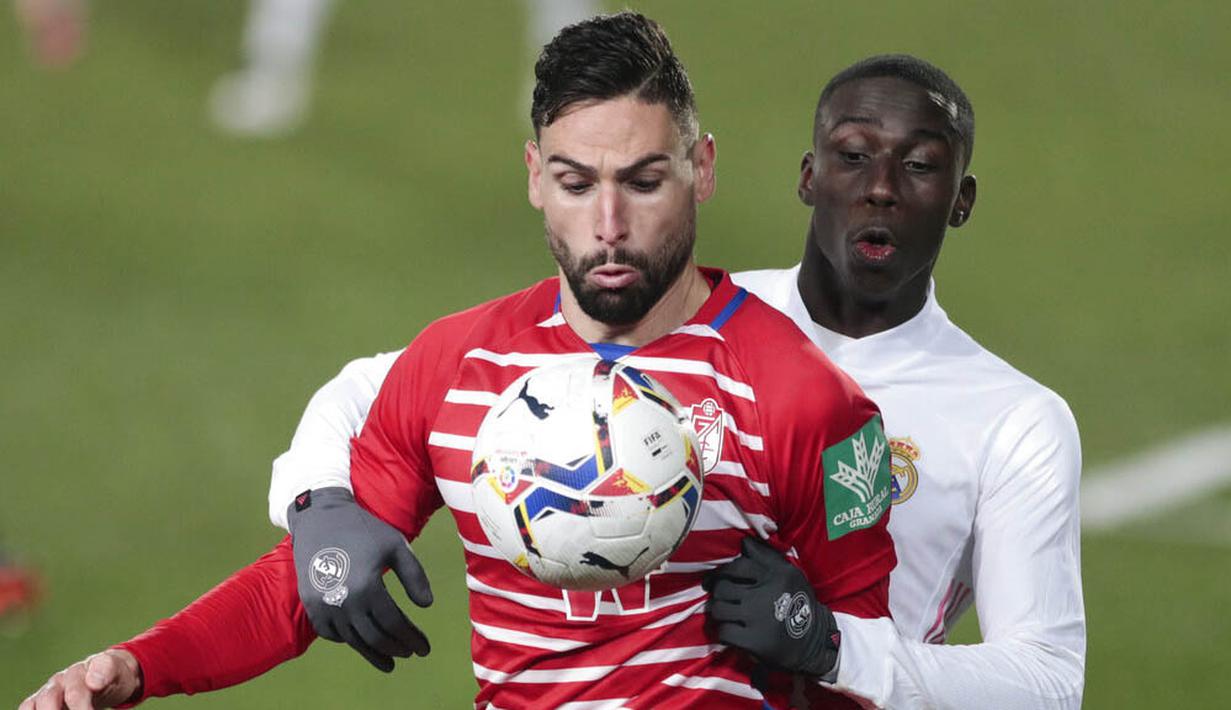 Pemain Real Madrid, Rodrygo, berebut bola dengan pemain Granada, Antonio Puertas, pada laga Liga Spanyol di Stadion Alfredo Di Stefano, Kamis (24/12/2020). Real Madrid menang dengan skor 2-0. (AP/Bernat Armangue)