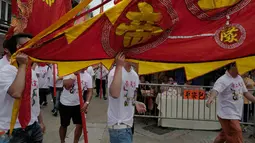 Penduduk setempat membawa bendera saat merayakan Festival Cheung Chau Bun di Hong Kong (5/3). Dulunya, festival ini digelar sebagai bentuk permohonan perlindungan dewa karena seringnya penyerangan yang dilakukan oleh para bajak laut. (AP Photo/Vincent Yu)