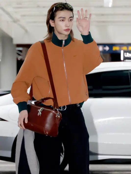Hyunjin Stray Kids tampil dengan atasan jaket orange sambil membawa Dior Archie Bag warna coklat.  Dok. Dior
