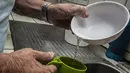 Seorang pria mencuci piring dengan air yang dikumpulkan karena penjatahan air di San Jose pada 12 Juli 2023. (Ezequiel BECERRA / AFP)
