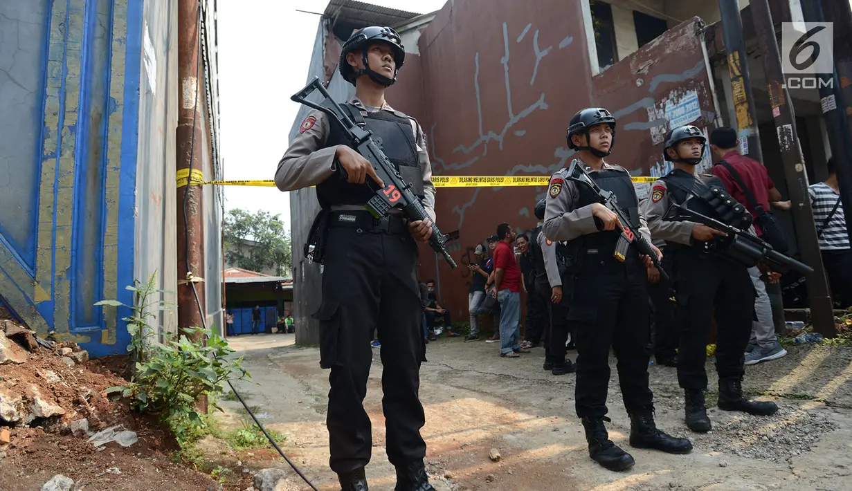 Polisi bersenjata berjaga-jaga saat berlangsungnya olah tempat kejadian perkara (TKP) di rumah terduga teroris di Nanggewer, Cibinong, Bogor, Jawa Barat, Sabtu (18/5/2019). Polisi menenteng senjata saat berjaga di depan gang menuju rumah terduga teroris Pak Jenggot. (merdeka.com/Imam Buhori)