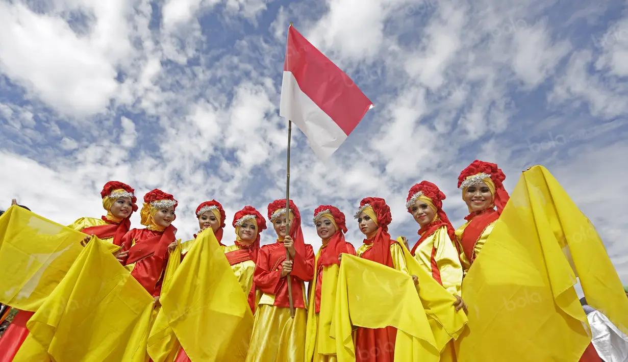Penari mengibarkan bendera Merah-Putih usai beraksi pada penutupan Tour de Singkarak 2016 di Kota Padang, Sumatera Barat, (14/8/2016). (Bola.com/Nicklas Hanoatubun)