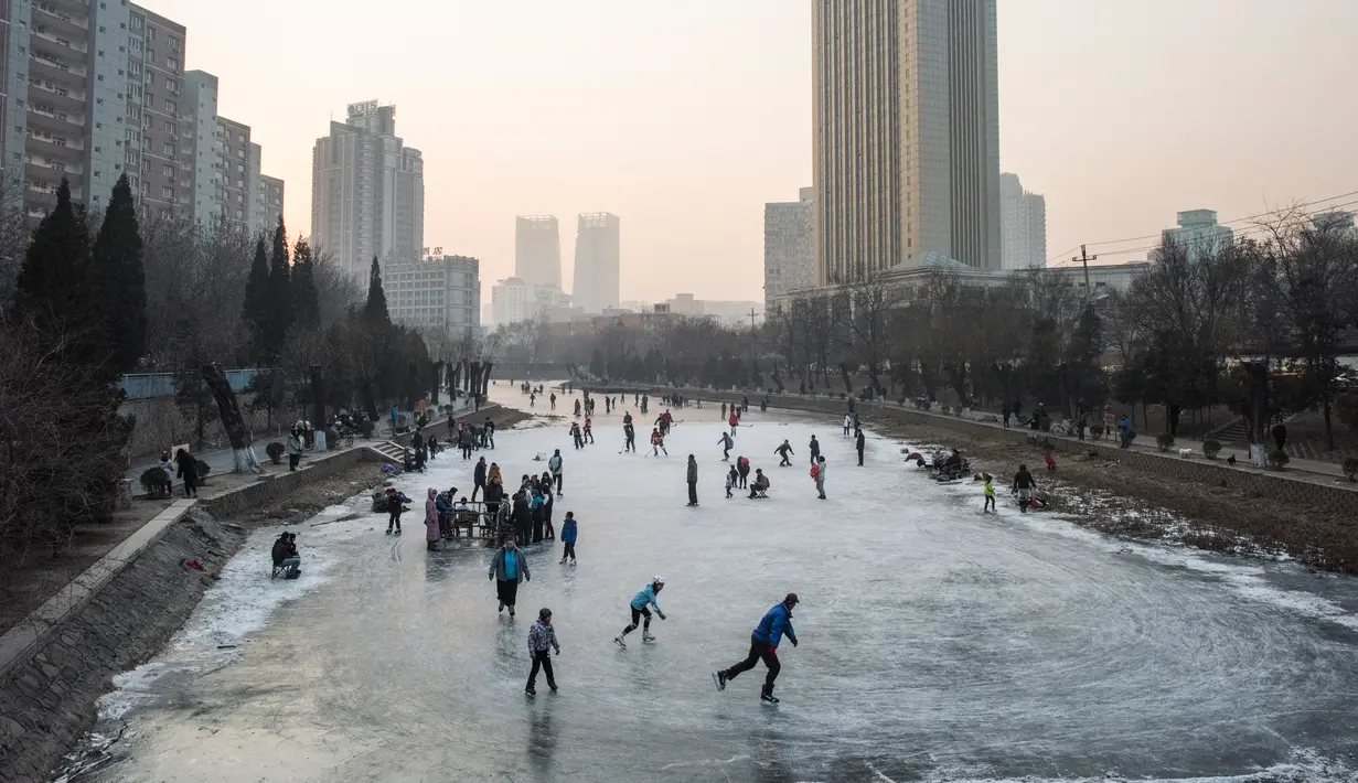Sejumlah warga tampak menikmat bermain ice skating atau seluncur es di atas sungai yang telah membeku di Beijing, Jumat (1/1). Semenjak membeku, sungai di Beijing ini menjadi objek wisata es dadakan yang banyak diminati wisatawan.  (AFP/Fred Dufour) 