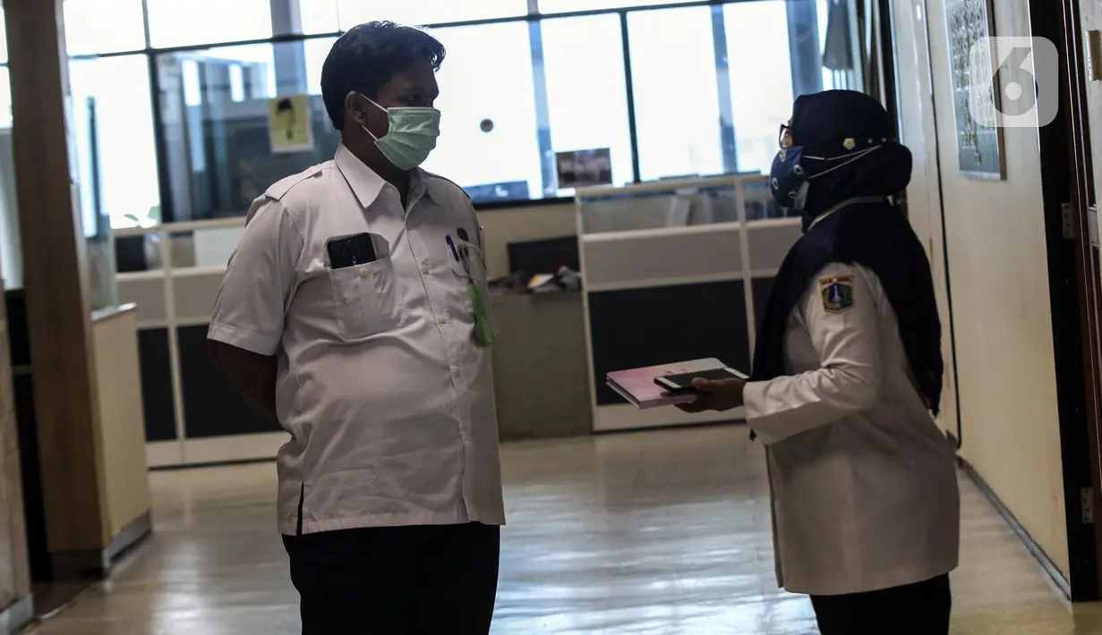 Pegawai Badan Kepegawaian Daerah DKI Jakarta berbincang di Kantor Balai Kota DKI Jakarta, Kamis (11/2/2021). Kementerian PANRB secara resmi melarang seluruh ASN bepergian ke luar kota saat libur Imlek guna mencegah penyebaran dan penularan COVID-19. (Liputan6.com/Johan Tallo)