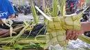Pedagang menunjukkan satu ikat kulit ketupat siap jual di Pasar Kemiri Muka, Depok, Jawa Barat, Selasa (12/6). Menjelang Lebaran, pedagang kulit ketupat mengaku kebanjiran pembeli. (Liputan6.com/Herman Zakharia)