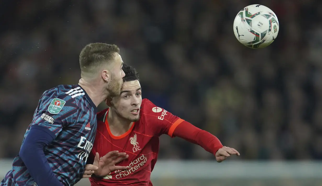 Bek Arsenal Calum Chambers berebut bola dengan gelandang Liverpool Curtis Jones pada leg pertama semifinal Piala Liga Inggris di Stadion Anfield, Jumat (14/1/2022) dinihari WIB. Arsenal dipkasa bermain imbang tanpa gol oleh Liverpool. (AP Photo/Jon Super)