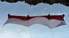 Sekelompok mahasiswa mengibarkan bendera Merah Putih berukuran besar menjelang perayaan Hari Ulang Tahun ke-77 Republik Indonesia di Pantai Lhoknga, Aceh, 16 Agustus 2022. Pengibaran bendera Merah Putih berukuran besar yang dilakukan pada sebuah tebing ini untuk memeriahkan Hari Ulang Tahun ke-77 Republik Indonesia. (CHAIDEER MAHYUDDIN/AFP)