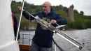 Ahli genetika Universitas Otago Profesor Neil Gemmell mengambil sampel air dari perairan Loch Ness, Drumnadrochit, Skotlandia, 11 Juni 2018. Tim dari Selandia Baru mengambil sekitar 250 sampel air untuk mengurai keberadaan monster legendaris asal Inggris, Loch Ness. (Andy Buchanan/AFP)