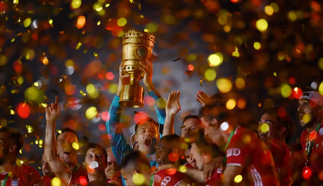 Penjaga gawang Bayern Munchen Manuel Neuer mengangkat trofi juara Piala Jerman (DFB Pokal) usai mengalahkan Bayer Leverkusen di Olympic Stadium, Berlin, Jerman, 4 Juli 2020. (Photo by ANNEGRET HILSE/POOL/AFP)