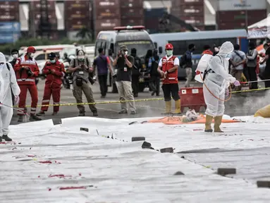 Petugas PMI menyemprotkan disinfektan pada hasil temuan dari pencarian Sriwijaya Air SJ 182 di Dermaga JICT 2, Jakarta, Minggu (10/1/2021). Penyemprotan rutin untuk mengantisipasi penyebaran COVID-19 dilakukan usai hasil temuan diidentifikasi tim DVI serta KNKT. (merdeka.com/Iqbal S. Nugroho)